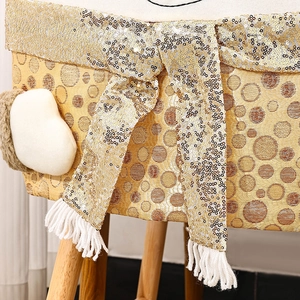 Detail of gold sequin Christmas chair cover featuring a large bow and white fringe tassels