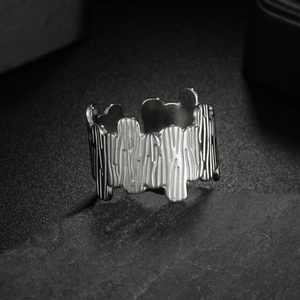 Silver geometric stainless steel ring with textured relief on a dark stone background