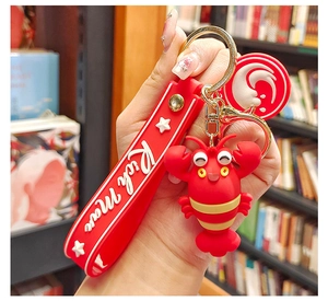 Close-up of a red cartoon lobster keychain with a Rich Man silicone wrist strap