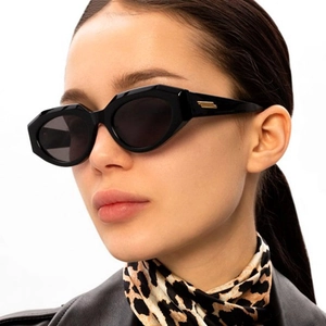 Detail of black irregular cat-eye sunglasses featuring golden metallic temple accents