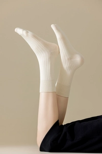 Gros plan de chaussettes en coton crème présentant une texture côtelée minimaliste