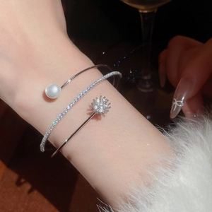Macro shot of three-layer silver spiral bracelet with pearls and zircon flower details