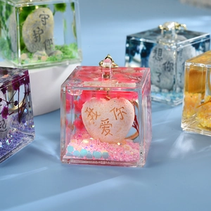 Macro detail of acrylic charm with pink dried flowers and engraved stones