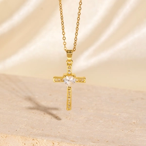 Gold plated hip hop cross necklace with heart shaped cubic zirconia on silk background