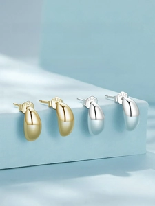 Close-up of S925 sterling silver moon stud earrings in gold and silver on blue stands