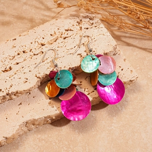 Vue détaillée de boucles d'oreilles en nacre colorée avec disques roses et bleus sur pierre