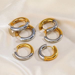 Polished two-tone gold and silver stainless steel chunky hoop earrings on beige silk