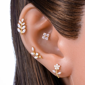 Titanium flower labret stud with golden leaves and crystals on model ear