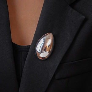 Polished silver metal teardrop brooch on a black suit jacket lapel for a modern look