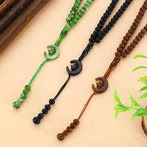 Detail of 99-bead Tasbih prayer beads in green, black and amber with crescent pendants