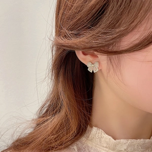 Macro shot of champagne gold butterfly earrings with zircon inlay on a model's ear
