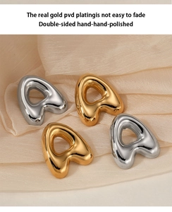 Detailed macro view of gold and silver letter A stud earrings on soft fabric