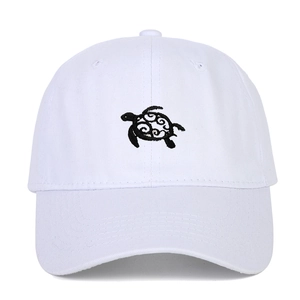 Close-up of detailed sea turtle embroidery on a white cotton baseball cap with twill texture