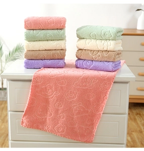 Close-up of embossed floral coral fleece towels in multiple pastel colors stacked on a drawer