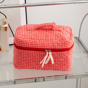 Detail of red and white checkered quilted cosmetic bag with ribbon zipper pulls