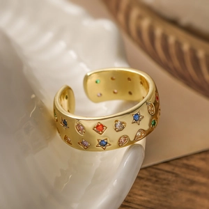 Golden open ring with colorful star and heart-shaped zircons in a minimalist geometric style