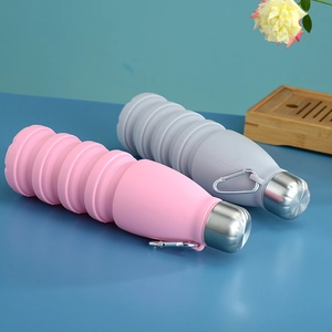 Detail view of pink and grey foldable silicone water bottles with metal caps and hooks