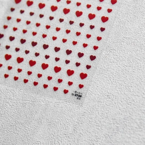 Detailed macro view of 3D red heart nail art stickers with self-adhesive backing