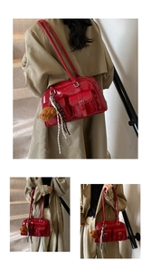 Close-up of red glossy vintage shoulder bag featuring metal buckles and a cute teddy charm