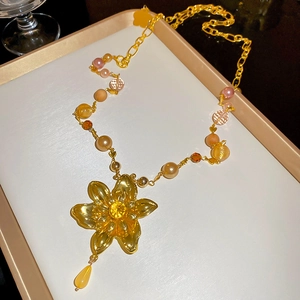 Détail du collier à pendentif fleur dorée avec perles mauves et cristaux jaunes