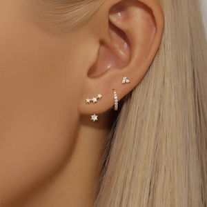 Detail of s925 silver gold bow earrings and turquoise studs set on woman's ear