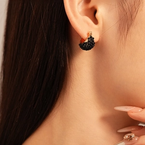 Close-up of vintage resin geometric basket hoop earrings worn on ear with gold and black beads