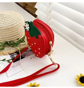 Detail of red strawberry-shaped PU leather bag with gold hardware and flower accents