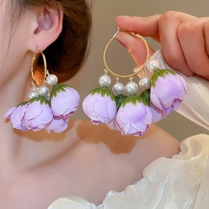 Detail of purple fabric flower earrings with white pearls and gold metal hoops on model