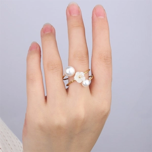 Vue détaillée d'une bague en acier doré 18k avec une fleur en nacre et perles blanches