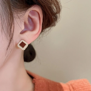 Gros plan de boucles d'oreilles carrées vintage émaillées avec perles sur modèle