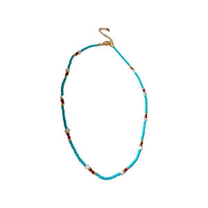Ethnic style pearl necklace with blue and red beads and gold clasp on white background