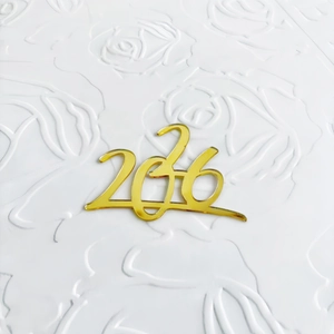Nahaufnahme der goldenen Acryl 2036 Kuchendekoration mit Glanz auf floralem Untergrund