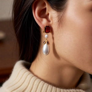 Macro view of vintage drop earrings with red gemstone and large waterdrop pearl