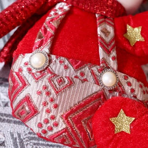 Detail of red velvet Christmas doll with gold brocade, sequins, and pearl button accents