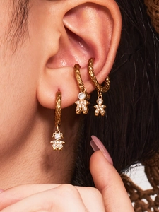 Detail of 18K gold astronaut earrings with 5A zircon and hammered texture on model