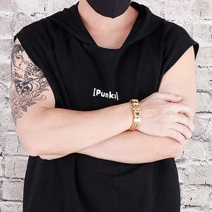 Close-up of men's chunky gold stainless steel punk bracelet worn on a black hoodie sleeve