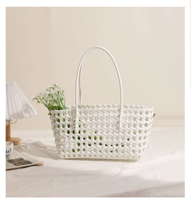 Detail of white hollow woven plastic beach bag featuring long handles and daisy flowers