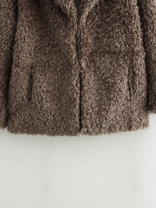 Close-up of thick brown faux fur texture on a warm designer coat with soft teddy plush
