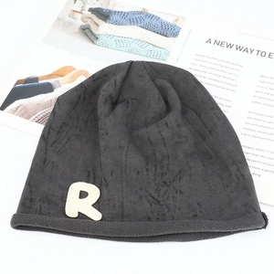 Détail du bonnet en maille gris foncé avec patch lettre R blanc et fini texturé doux