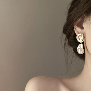Baroque pearl earrings with golden metal rose detail worn by model in a profile view