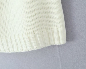 Close-up of white knitted fabric texture showing premium ribbed hem detail and soft material