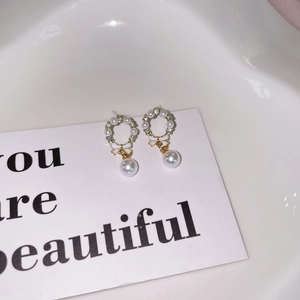 Close-up of pearl wreath bow earrings with gold plating and sparkling crystals