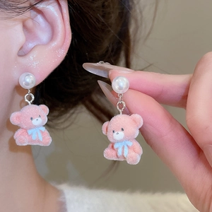 Detail of pink flocked teddy bear earrings with white pearls on model's ear