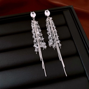 Détail macro de boucles d'oreilles à pompons argentés avec zircon ovale et chaînes