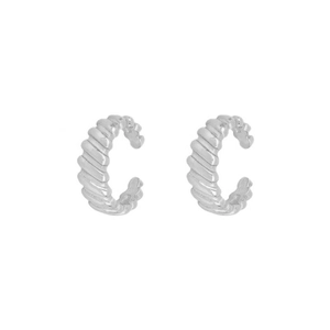 Macro view of silver croissant ear cuffs showing detailed metallic spiral texture