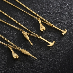 Macro shot of gold mini tool pendants featuring wrench, hammer, and screwdriver necklace