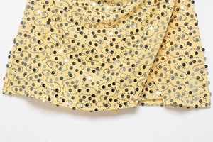 Detail shot of swirling black and silver sequins on yellow fabric of the mini skirt