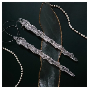 Macro detail of transparent icicle ornament with silver glitter on dark festive background
