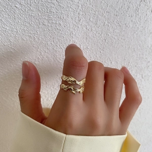 Close-up of stacked irregular gold S925 silver rings with lava-like textured surface