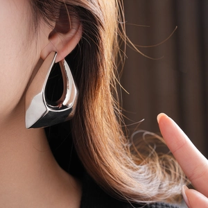 Close-up of irregular silver geometric stud earring worn on model for modern style